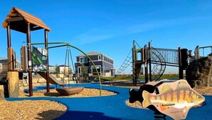 A playground with a swing set, a slide, and a climbing structure. - Clean, Cozy, Comfy & Modern (Calgary)
