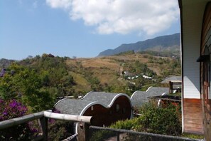 A view from a building with a wooden balcony overlooking a valley with houses and mountains. - Kiri Pura Resort Khao Kho (Khao Kho)