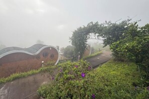 A brick building with a curved roof and circular windows, surrounded by greenery and a pathway. - Kiri Pura Resort Khao Kho (Khao Kho)