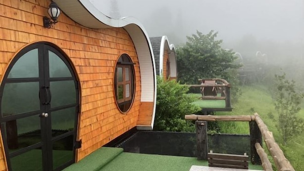 A row of wooden cabins with arched windows and a green outdoor area.