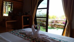 A hotel room with a bed, a window, and a view of the outdoors.