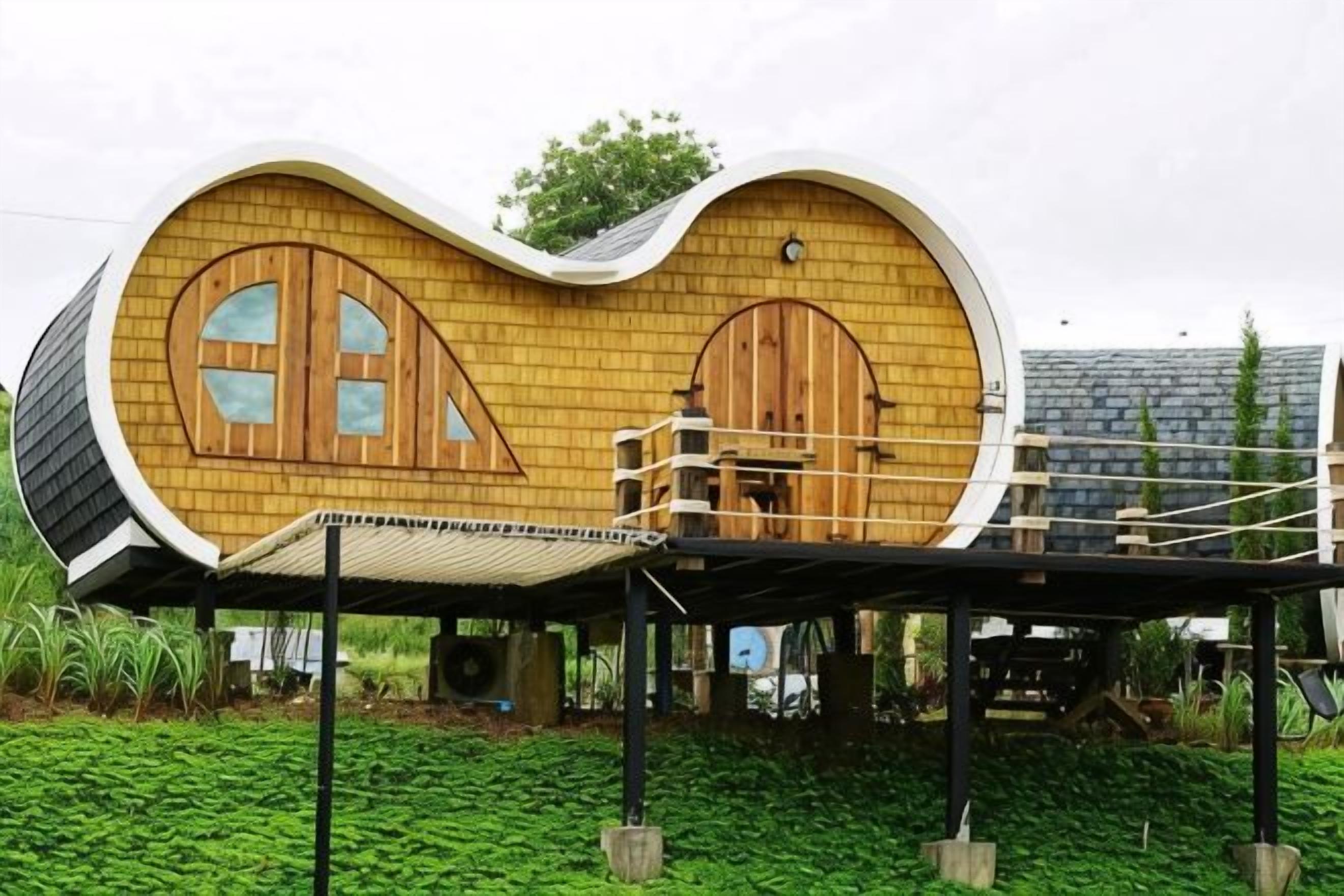 Ein einzigartiges, gebogenes Gebäude mit Holztüren und -fenstern, einem überdachten Gang und einer grünen Landschaft.