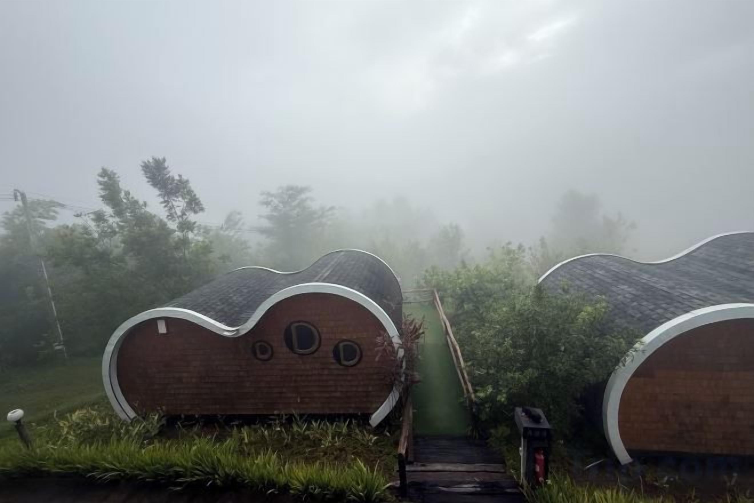 Deux structures uniques, dotées de toits incurvés, se dressent dans un décor extérieur brumeux.