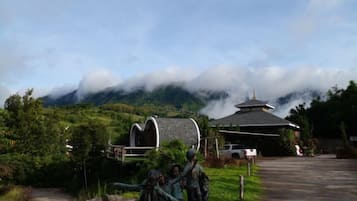 A traditional building with a curved roof, surrounded by lush greenery and mountains in the background.