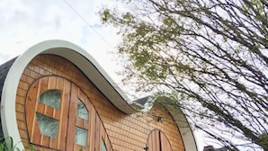 A modern building with a curved facade, large wooden doors, and a brick exterior.