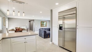 A modern kitchen with white cabinetry, a stainless steel refrigerator, and pendant lighting. - 7 Mi to Fremont St: Vegas Home w/ Backyard Oasis! (North Las Vegas)