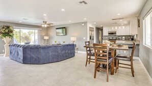 A modern kitchen with white cabinets, a dining area with wooden chairs, and a large window providing natural light. - 7 Mi to Fremont St: Vegas Home w/ Backyard Oasis! (North Las Vegas)