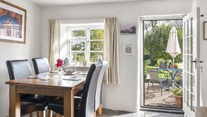 Un coin repas avec une table en bois, des chaises noires et un luminaire suspendu en cuivre.