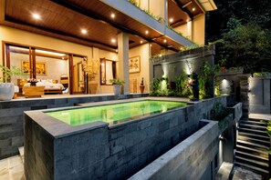 Un hotel moderno con piscina, zona de comedor y una escalera que lleva a un nivel superior.