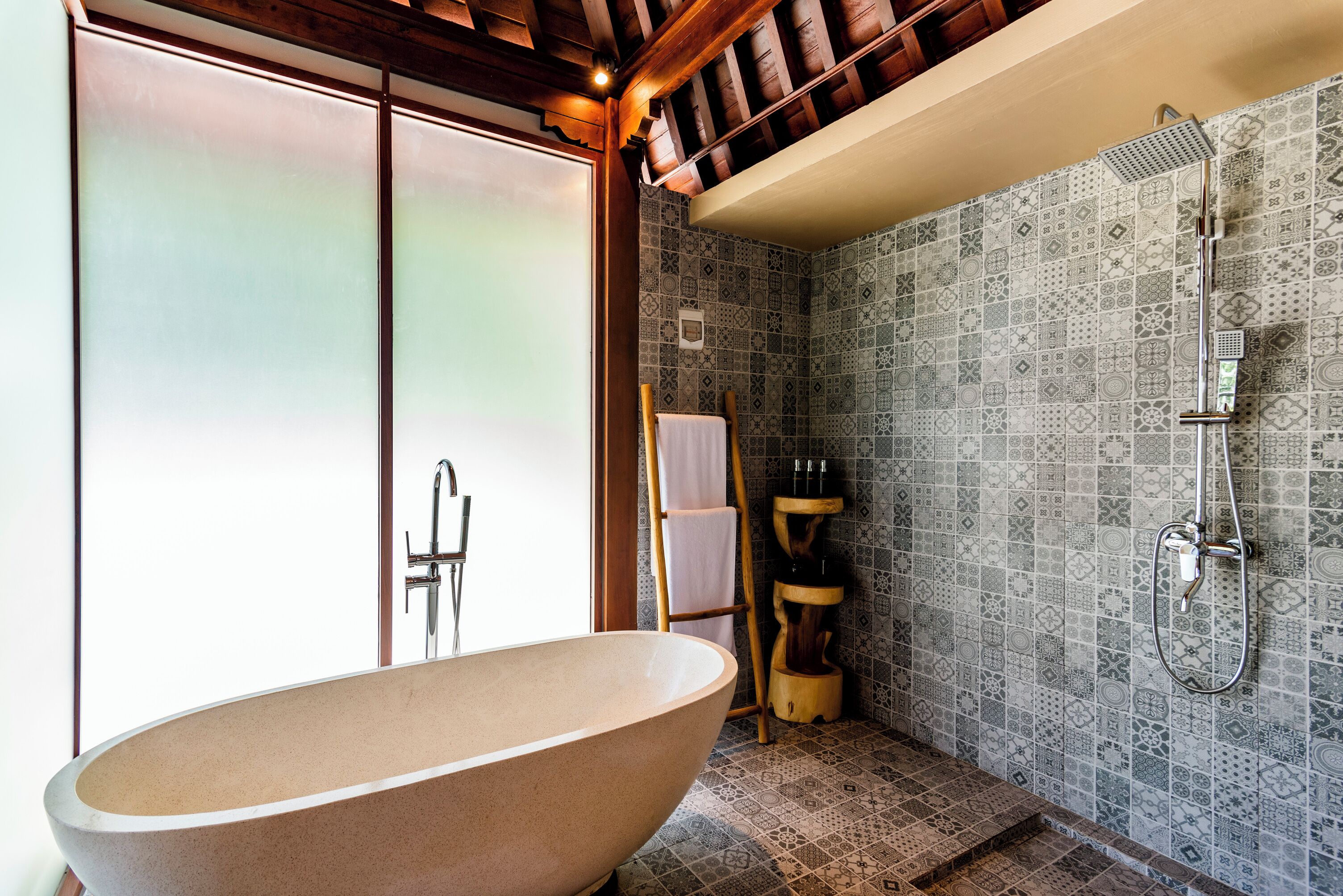 A bathroom with a freestanding bathtub, a shower, and patterned tiles.