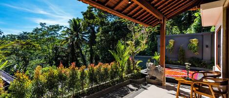 A covered patio with a view of lush greenery and a koi pond.