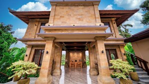 A traditional building with a central entrance, flanked by two columns, leading to a reception area with a desk and chairs. - Ellena Hilltop Resort Ubud by Dhananjaya Hospitality (Sebatu)