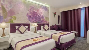 Habitación de hotel con dos camas, un mural floral grande, cabecera morada y vista a la ciudad a través de cortinas.