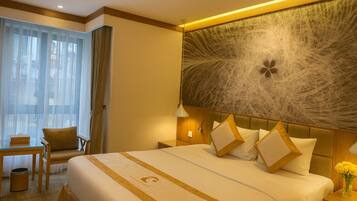 A hotel room with a large bed, a desk, and a chair.