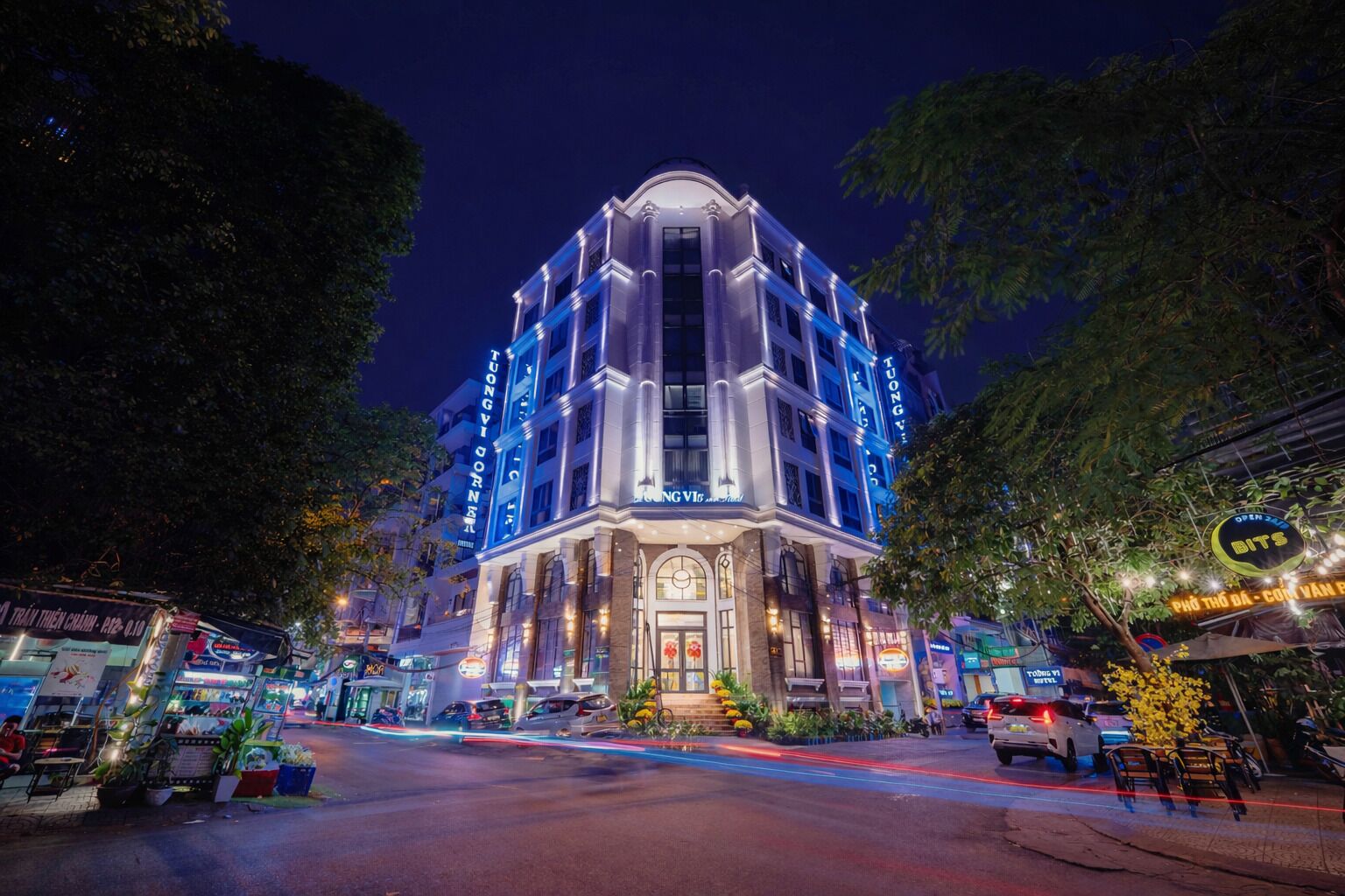 Un hotel de varios pisos con una entrada destacada, señalización iluminada y fachada bien iluminada.