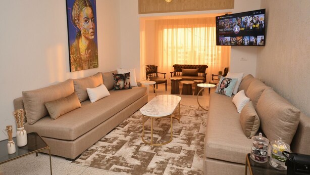Una sala de estar con un sofá color beige, una mesa de centro y un televisor montado en la pared.
