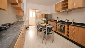 Una cocina moderna con armarios de madera, una mesa de comedor con sillas y un refrigerador.