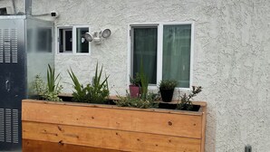 Ein Gebäude mit weißem Stuckputz, einem roten Dach und einem großen hölzernen Pflanzgefäß mit Pflanzen.