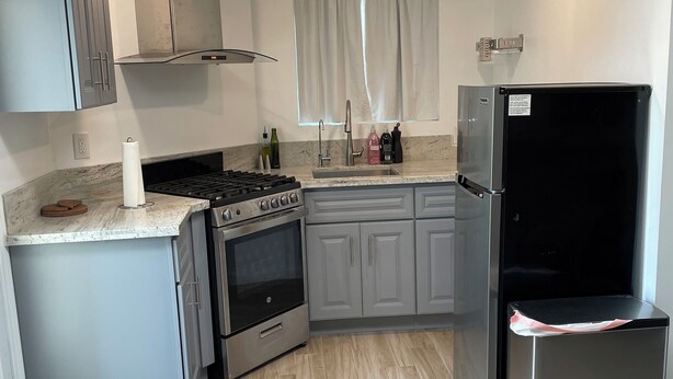 Eine moderne Küche mit grauen Schränken, einem Edelstahl-Kühlschrank, einem Gasherd und einem eingebauten Backofen.