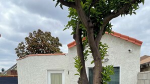 Ein kleines Haus mit weißer Fassade, rotem Dach und einer Tür mit Fensterteil.