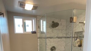 Ein Badezimmer mit Toilette, einer Duschkabine und einem weißen Waschbecken.