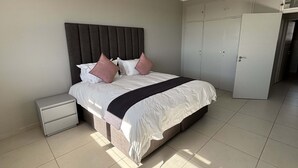 Ein Schlafzimmer mit Bett, Nachttisch, Kleiderschrank und Tür.
