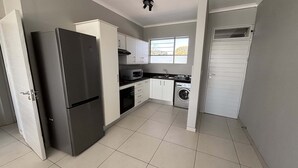 Eine kompakte Küche mit Kühlschrank, Backofen, Mikrowelle und Waschmaschine.