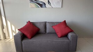 Ein graues Sofa mit zwei roten Kissen, einem hölzernen Couchtisch und einer Wanddekoration aus Marmor.