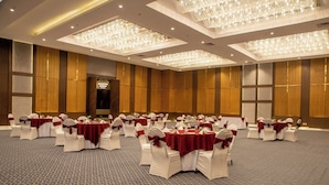 A large banquet hall with round tables and white chairs, each with a red tablecloth and matching chair covers.