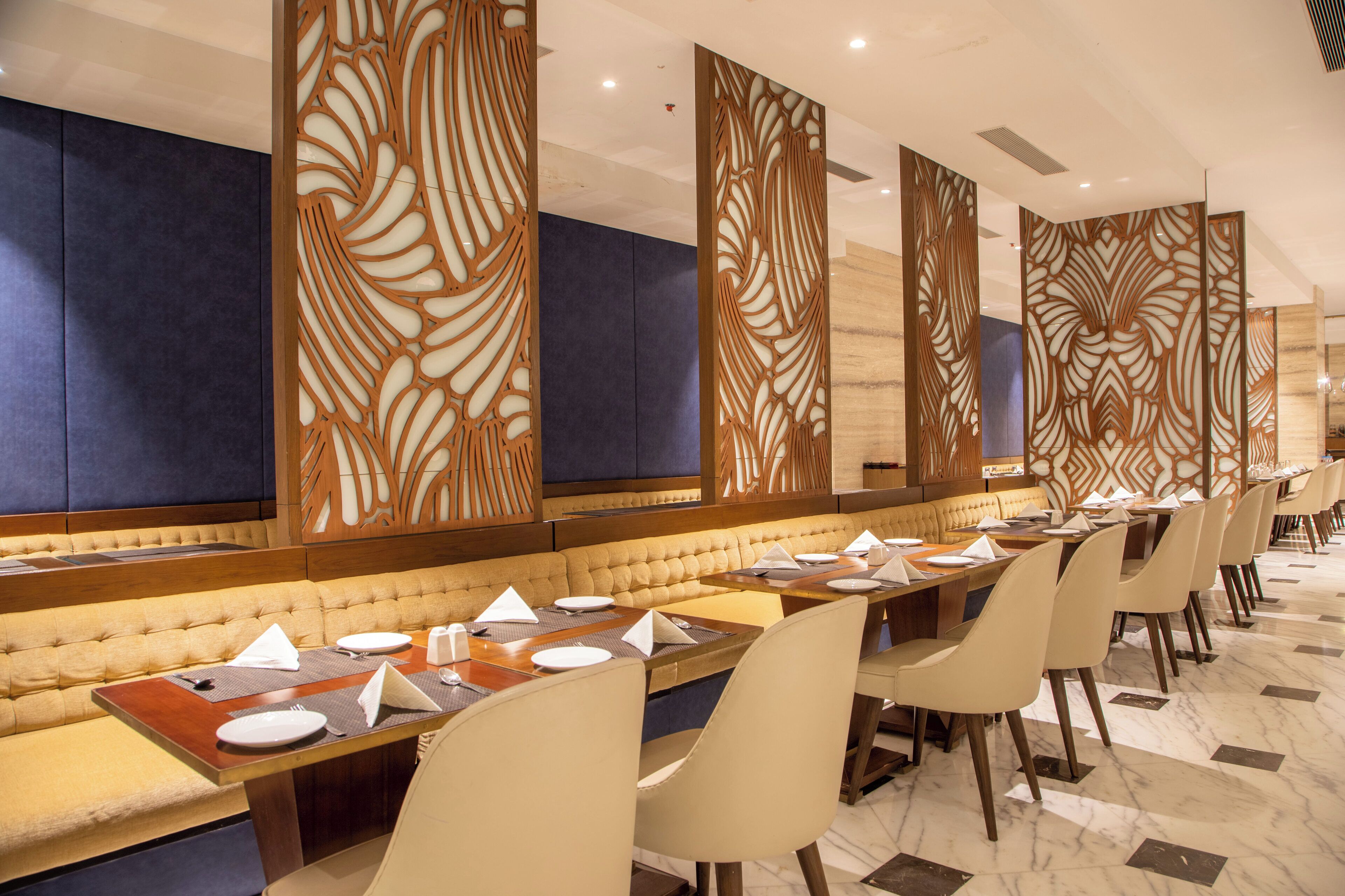 Una larga mesa de comedor con múltiples sillas, un banco acolchado y paneles decorativos en las paredes.