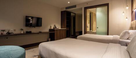 A hotel room with a large bed, a small sofa, a TV mounted on the wall, and a mirror.