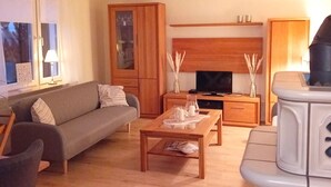 Un salon comprenant un canapé, une table basse et un téléviseur. On y trouve également un meuble avec des portes en verre et un meuble en bois.
