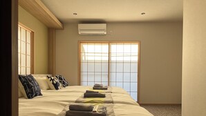 Een hotelkamer met een groot bed, een schuifdeur van shoji-schermen en een airconditioner.