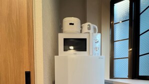 Een kleine keuken met een witte koelkast, een magnetron en een koffiezetapparaat erboven.