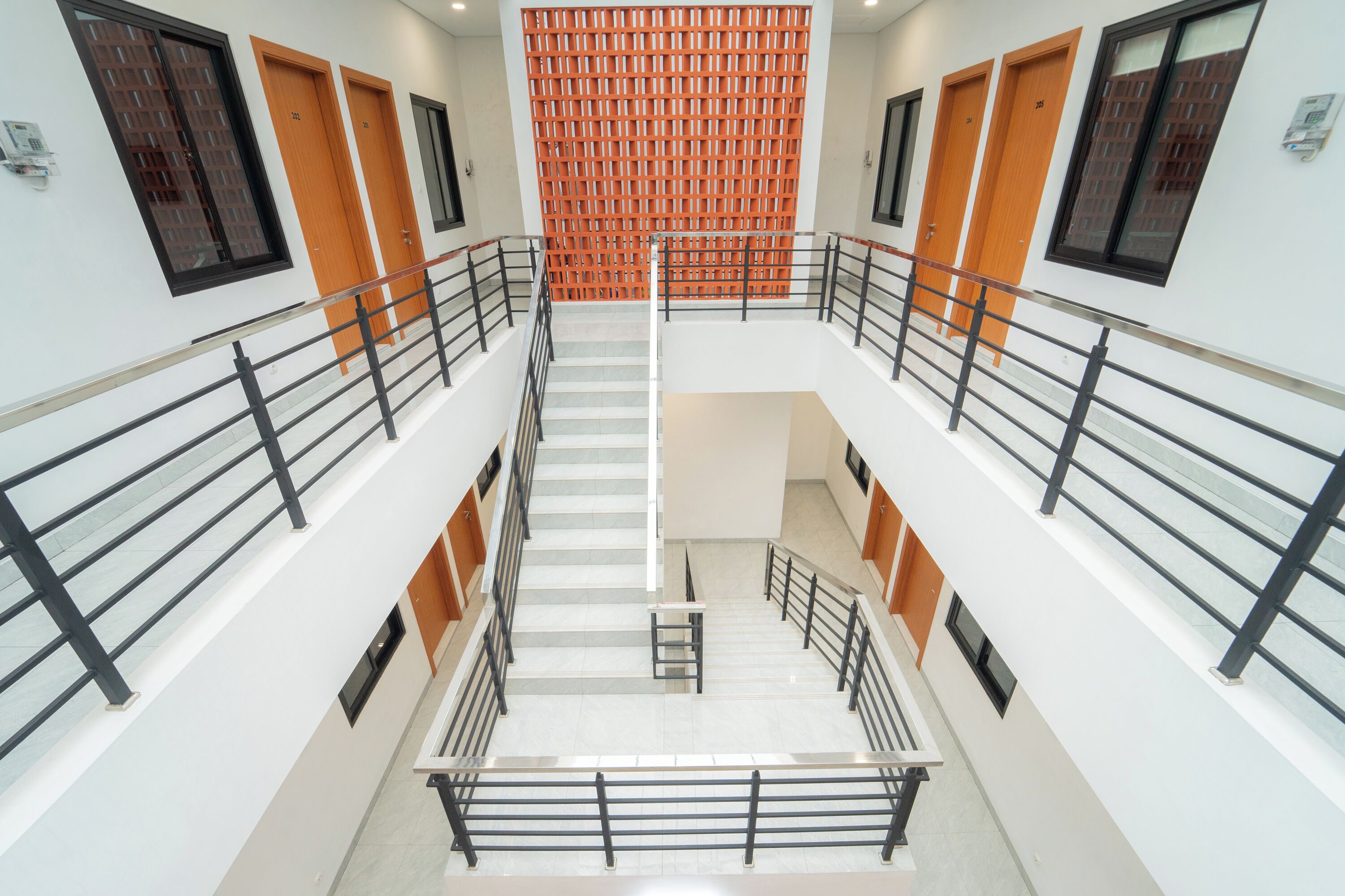 A multi-level interior with a central staircase, metal railings, and wooden doors.