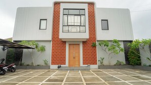 Un edificio moderno con un área de entrada con baldosas, una puerta central y dos ventanas.