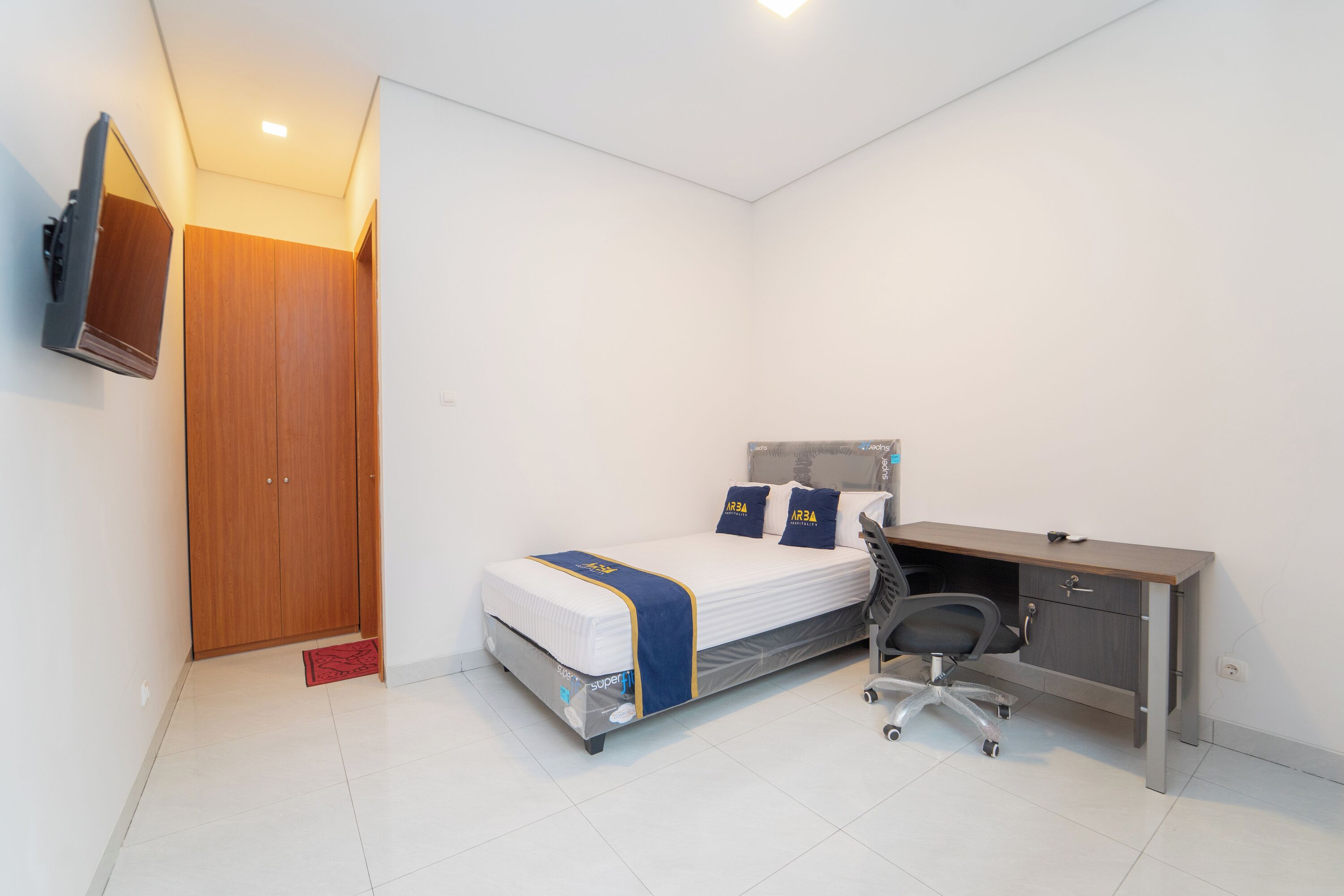 Ein Schlafzimmer mit Bett, Schreibtisch, Stuhl und Kleiderschrank.