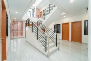 Un interior moderno con una escalera central, puertas de madera y piso de baldosas.
