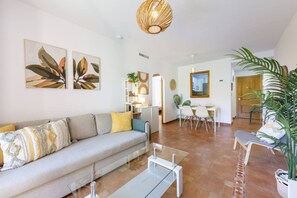 Een moderne woonkamer met een bank, salontafel en een eetgedeelte met stoelen.