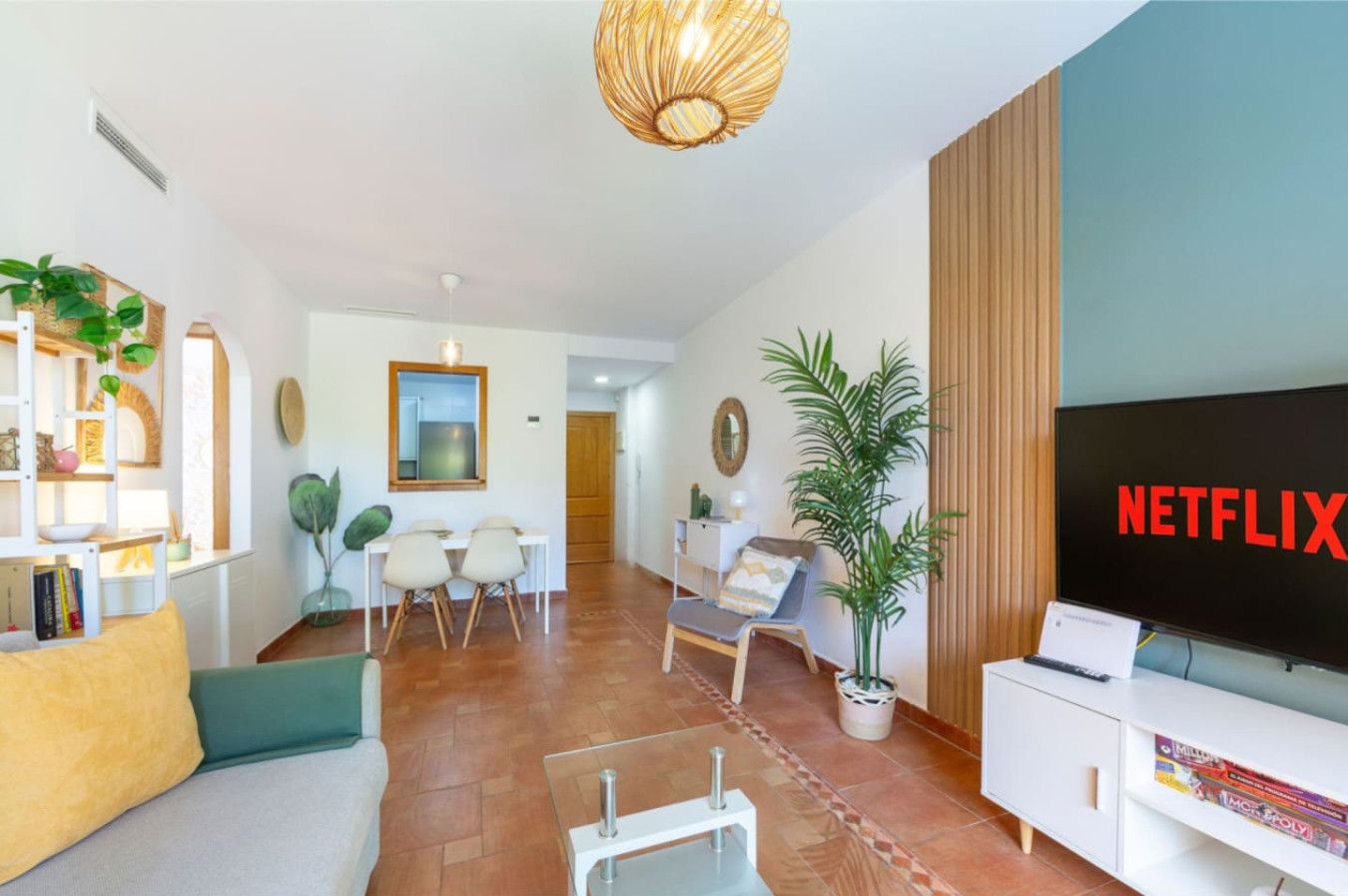 Un salon moderne doté d’un téléviseur à écran plat, d’un canapé, d’une table basse et d’un coin repas avec des chaises et une table.
