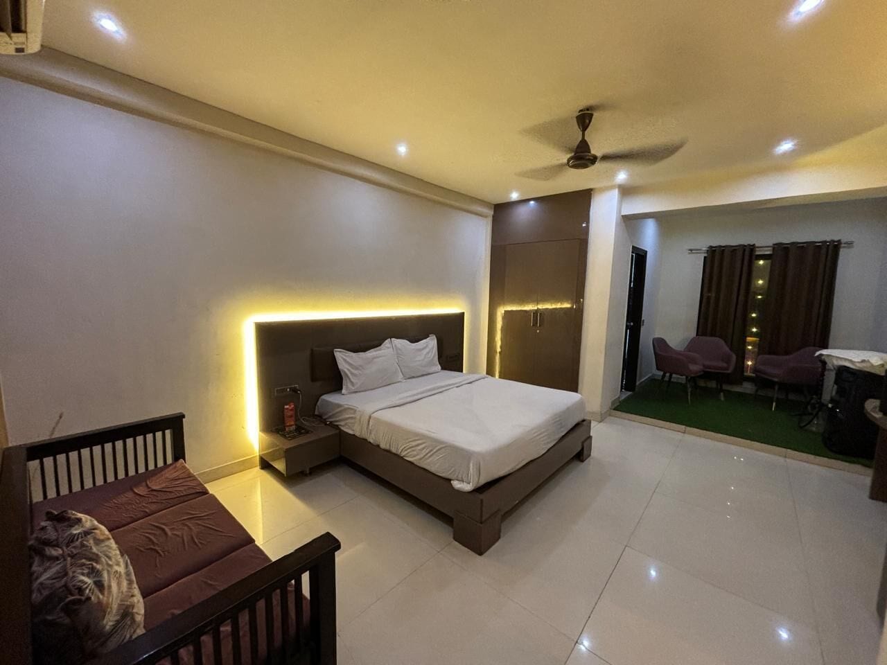 Une chambre à coucher moderne, comprenant un lit, une table de chevet et un petit coin salon avec une chaise et une table.