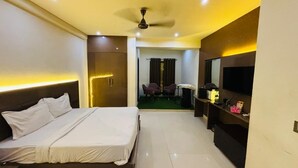 Quarto de hotel com cama, televisão, escrivaninha e cadeira.