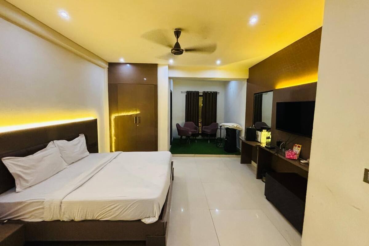 A hotel room with a bed, a TV, a desk, and a chair.