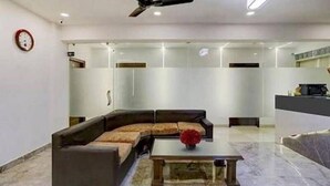 Uma sala de estar moderna com um sofá seccional, uma mesa de centro e um vaso de flores vermelho.