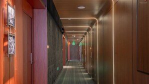 Un pasillo con paredes de madera, alfombra estampada e iluminación empotrada.