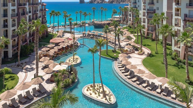 A resort with multiple swimming pools, palm trees, and beachfront views.