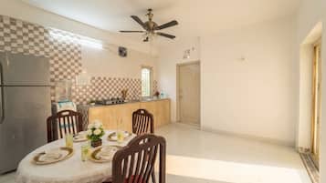 A dining area with a table set for four, a kitchen with a refrigerator and stove, and a ceiling fan.