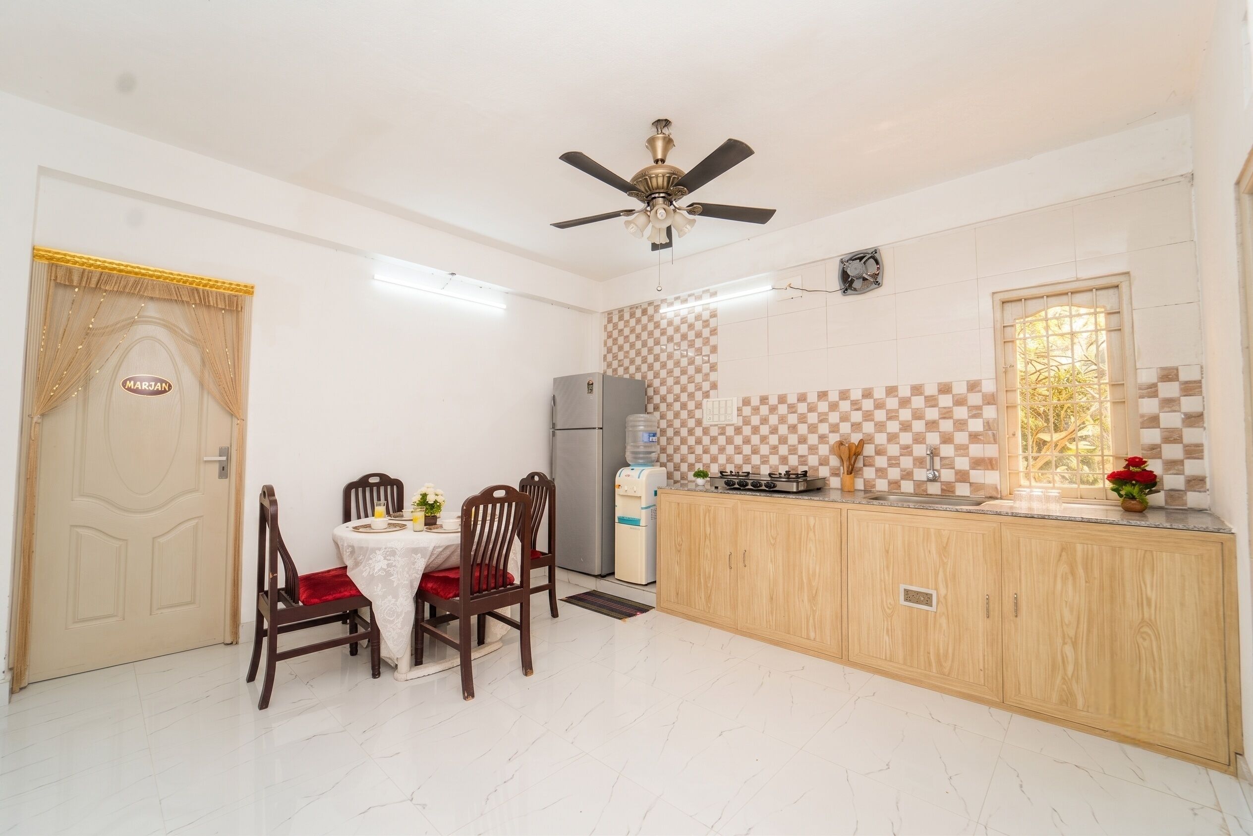 A compact kitchen with a dining area, a ceiling fan, a refrigerator, and a window with a view.