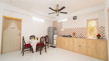 A compact kitchen with a dining area, a ceiling fan, a refrigerator, and a window with a view.