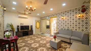 A living room with a sofa, a television, a water dispenser, and a patterned carpet.
